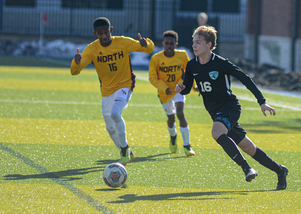 Landon Petri of Tolton Catholic High School dribbles past two Lutheran North High School defenders
